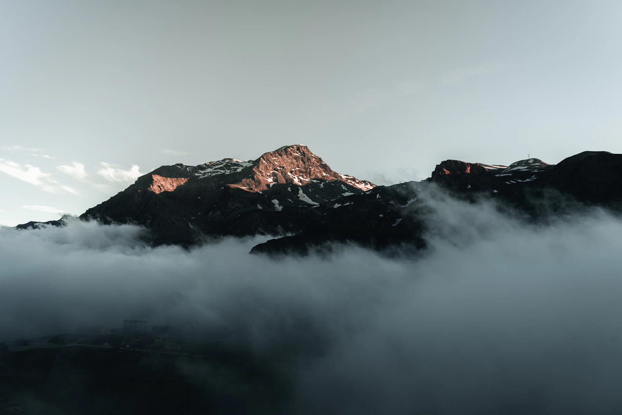 A mountain peak lit by dawn above a sea of cloud